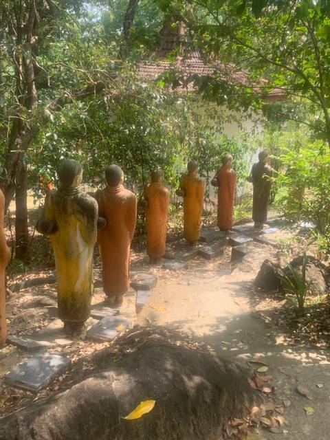Group of stone statues under trees.
