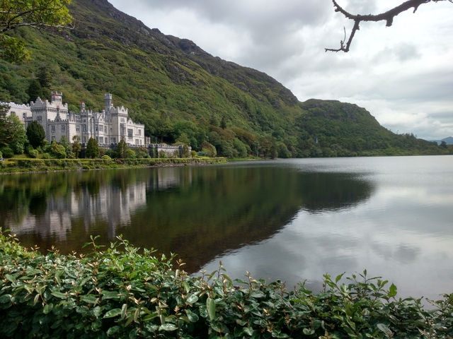 A beautiful castle by a lake surrounded by lush greenery.