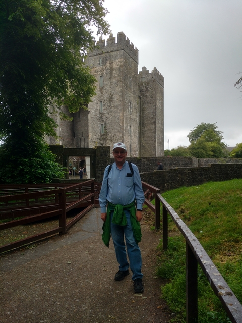 A man standing in front of a castle with an overcast sky.