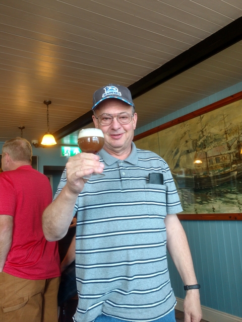 A man holding a glass of beer inside a pub.