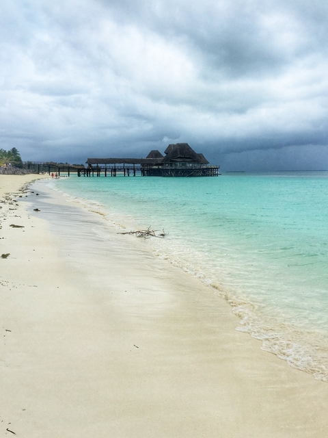 Beach with turquoise water and a wooden structure on stilts.
