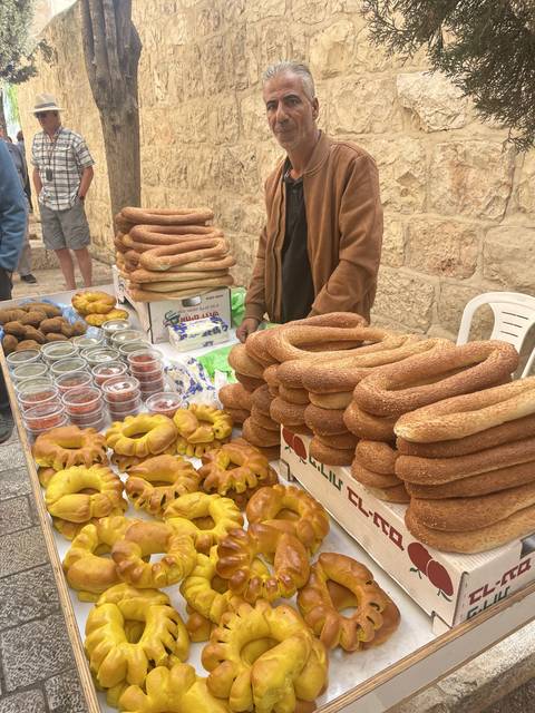       A vendor selling an assortment of breads and pretzels at a market stall.
  