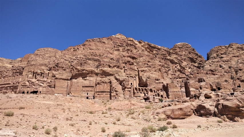 Rocky landscape with carved structures against a clear blue sky.
