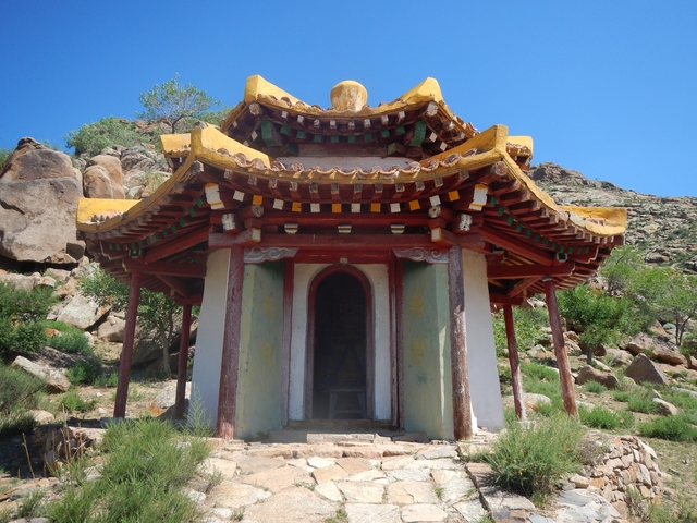 Small ornate temple in a mountainous rocky landscape.