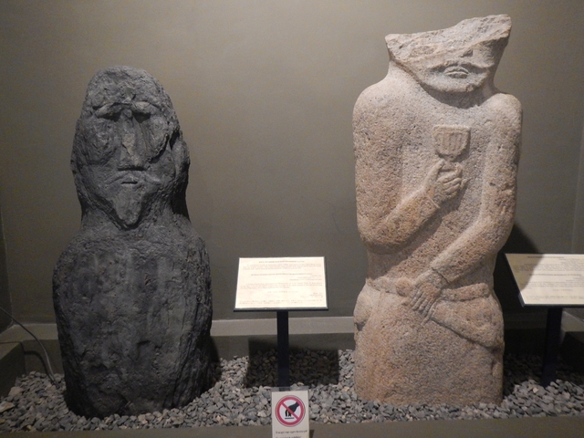 Ancient statues displayed indoors with informational plaques.