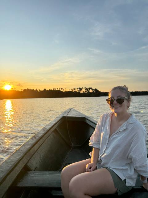 Person sitting in a boat during sunset.