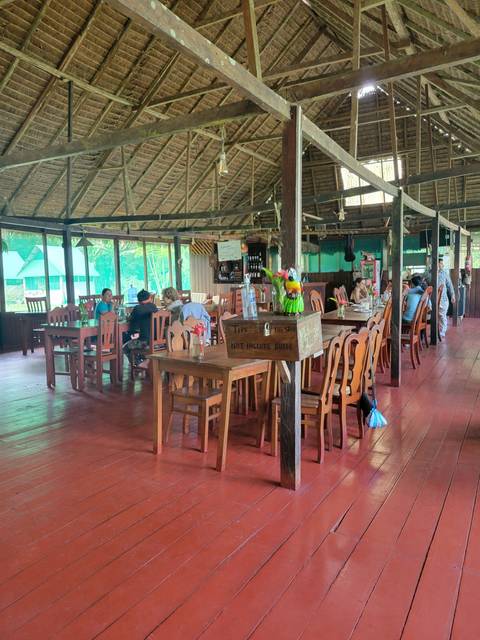       People dining in an open-air wooden structure.
  
