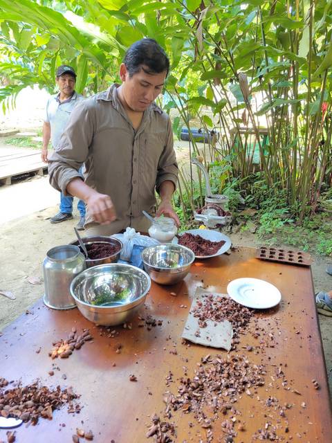       People preparing food outdoors at a table.
  