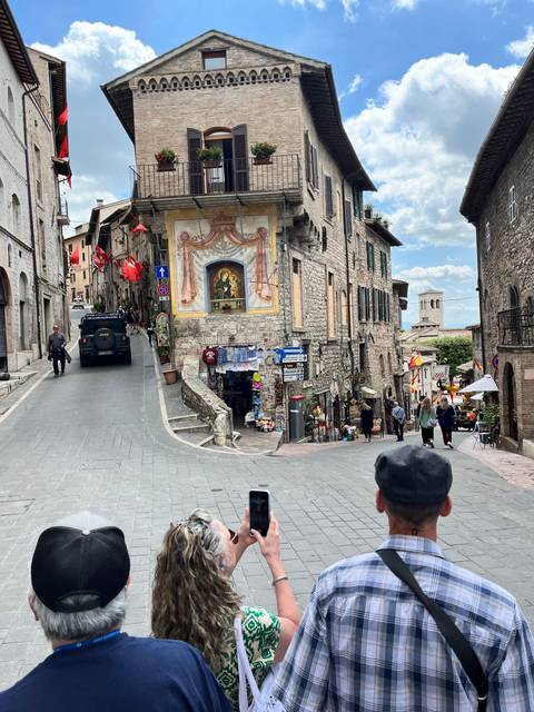 Stone building with a colorful painting and people taking photos.
