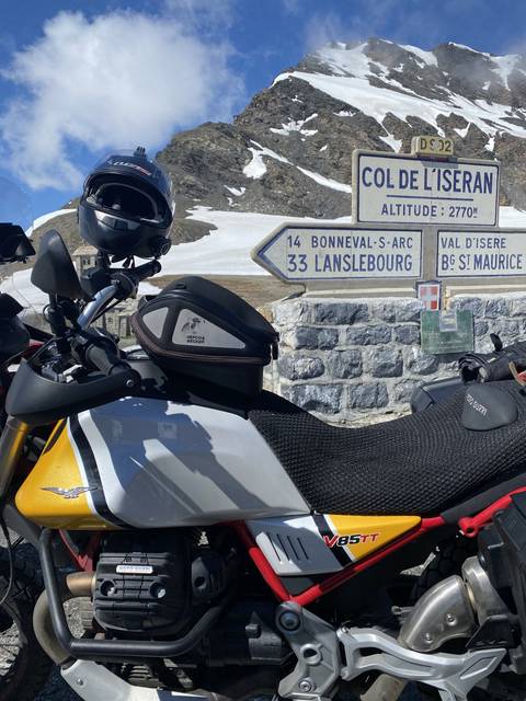       A motorcycle parked at a sign for Col de l'Iseran.
  