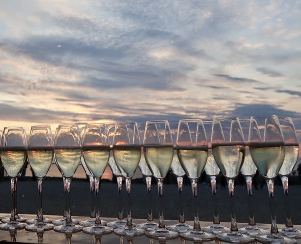 Champagne glasses lined up with a sunset in the background.
