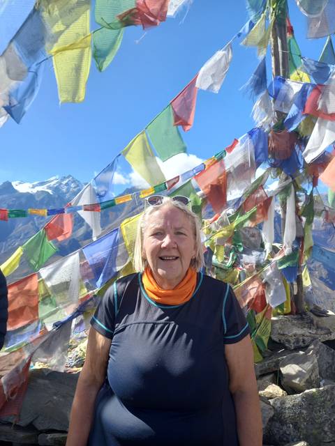 A person in front of colorful prayer flags.