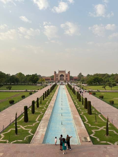       Gardens with a reflection pool leading to a large gateway.
  
