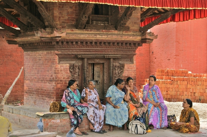       Women sitting and chatting around a traditional architecture in Kathmandu.
  