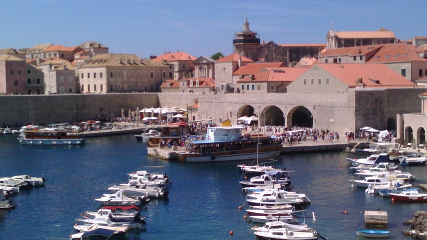 Harbor filled with boats against a historic stone wall.