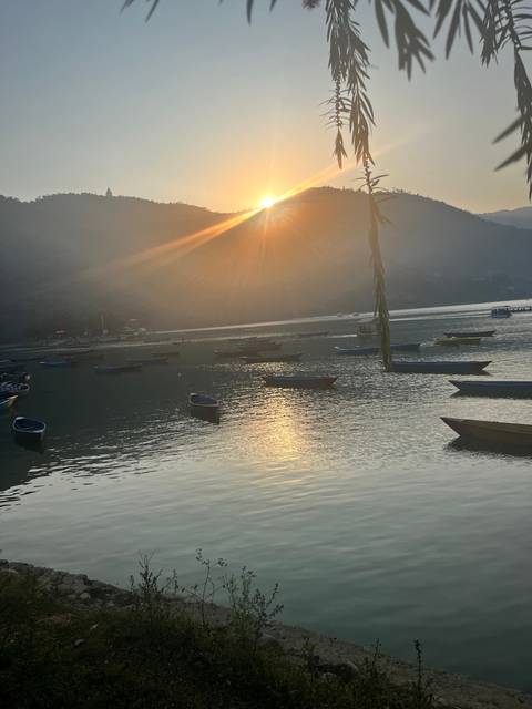 Serene lake at sunset with boats on the water.