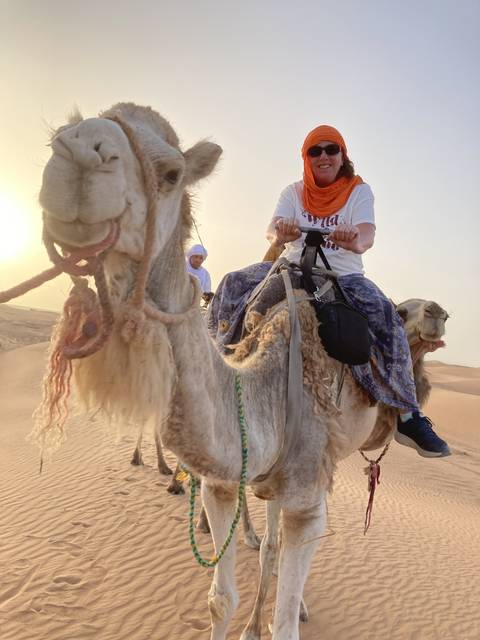 Person riding a camel in a desert setting.