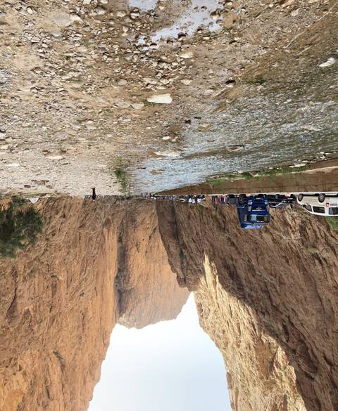 Narrow gorge with water flowing and some transport vehicles.