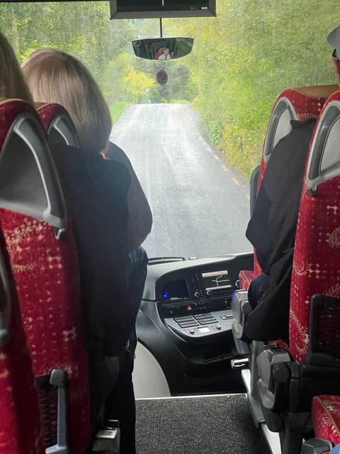       Interior view from a bus looking out at a rainy road.
  
