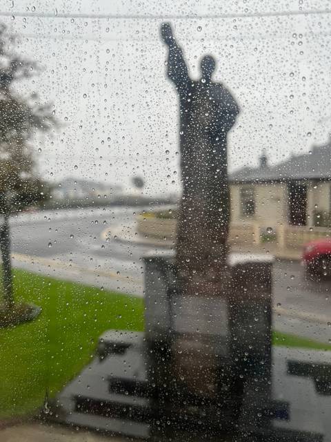       Blurry silhouette of a statue seen through a rain-specked window.
  
