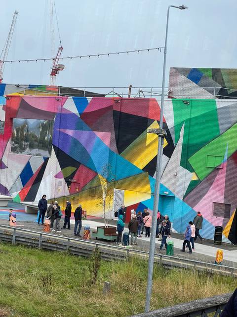 Brightly colored geometric mural with people standing nearby.