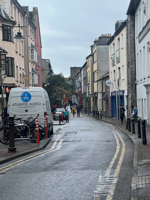       Street view of a town with people walking and a parked van.
  