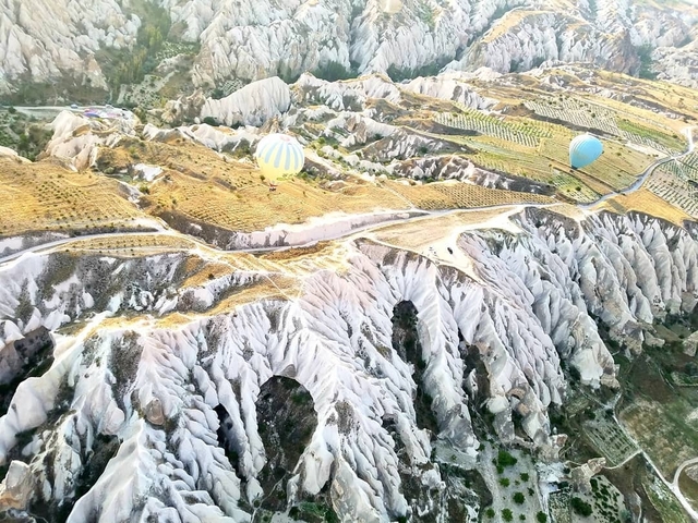 Aerial view of rocky valleys and hot air balloons.