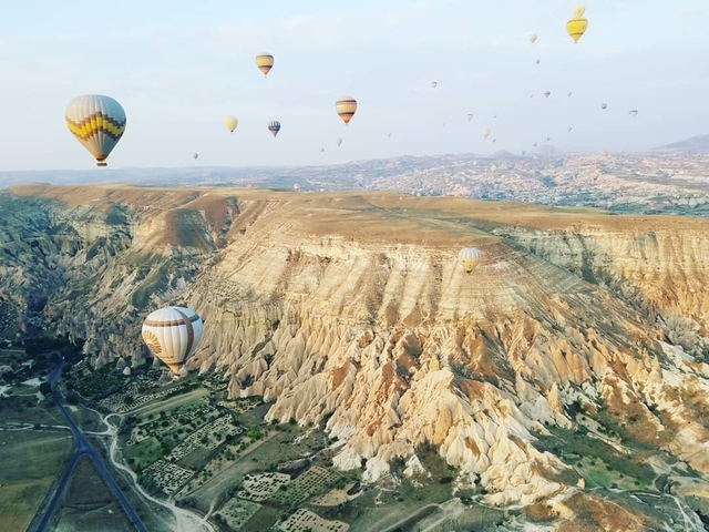 Hot air balloons over a rocky Cappadocia landscape.