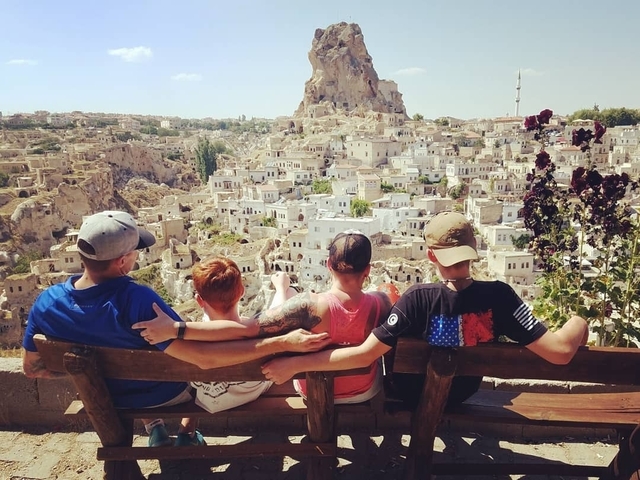 People sitting on a bench overlooking Cappadocia town.