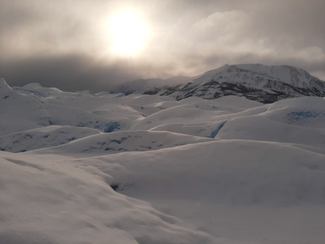Snow-covered landscape with rolling hills and a foggy atmosphere.