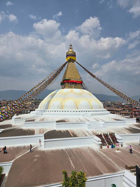       Large stupa surrounded by prayer flags viewed at an angle.
  