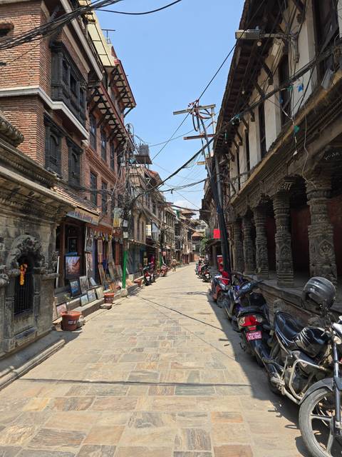       Street with historical buildings and scooters parked.
  