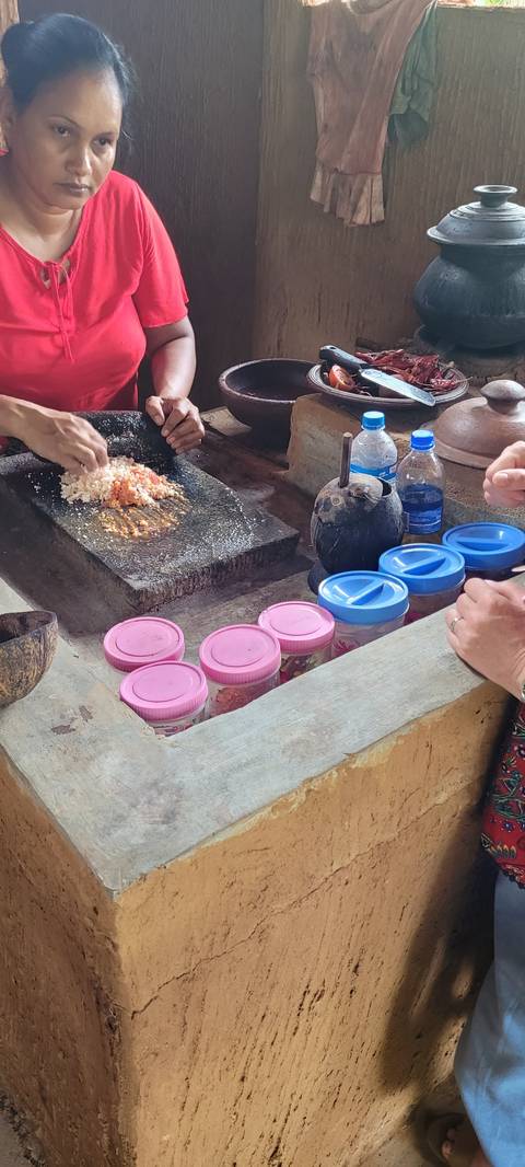       People preparing food at a traditional cooking station.
  