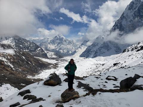 Hiker in snowy mountains with clouds and snow-covered peaks.