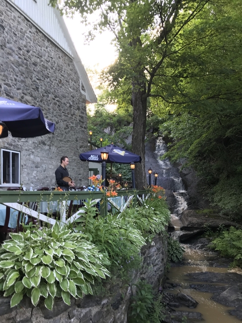       Waterfall next to a patio with tables and chairs.
  