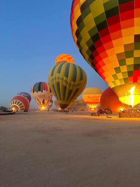 Hot air balloons being prepared and lit at a launch site.