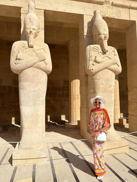       Person posing beside large stone statues in a temple.
  