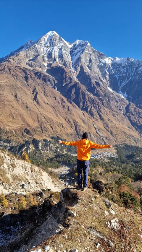 Person standing with arms outstretched in front of mountains.