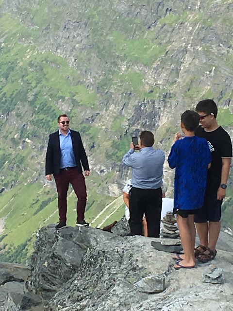 A small group of people on a mountain hike with rocky terrain.