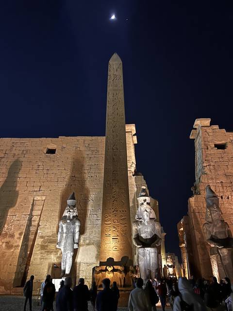       Ancient Egyptian temple with hieroglyphs and statues lit at night.
  