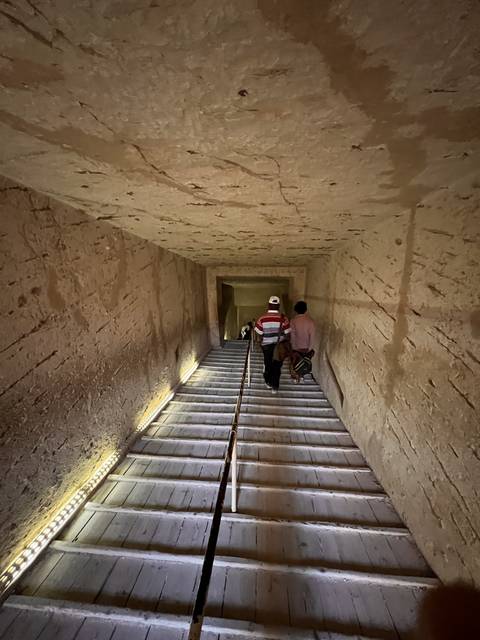       Descending a narrow wooden staircase in an ancient corridor.
  