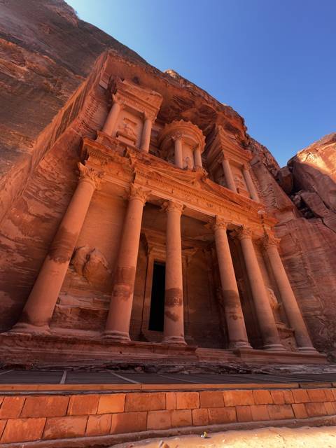       The Treasury of Petra carved into red sandstone cliffs.
  