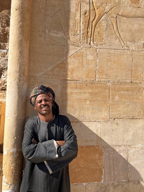       Man posing in front of ancient stone carvings.
  
