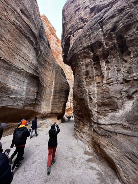      Tourists walking through a narrow canyon path.
  