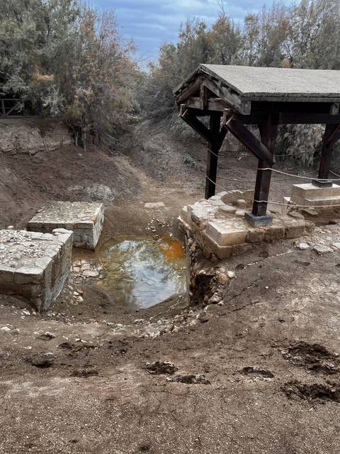       Small pool of water with a rustic shelter nearby.
  