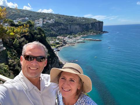       Couple posing with a coastal town and sea in the background.
  