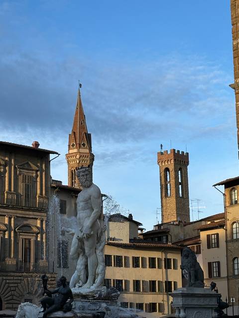       Statue with gothic architecture in a town square.
  