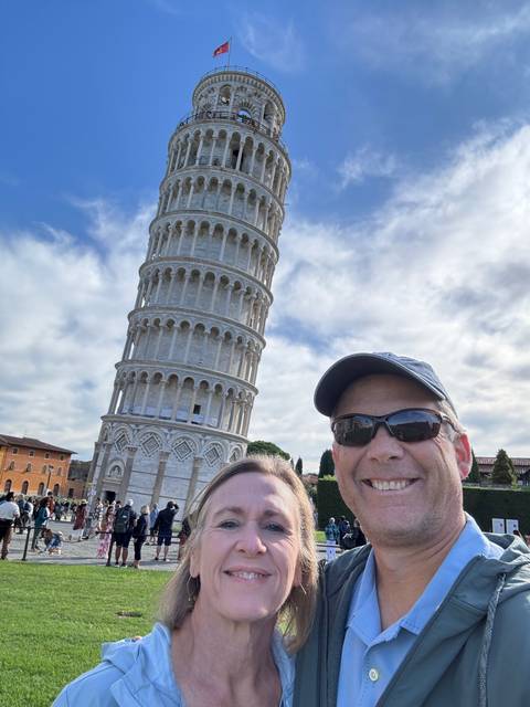       Couple posing with the Leaning Tower of Pisa in the background.
  