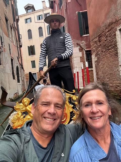       Couple in a gondola on a canal in Venice.
  