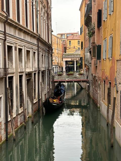       Gondola on a canal surrounded by buildings in Venice.
  